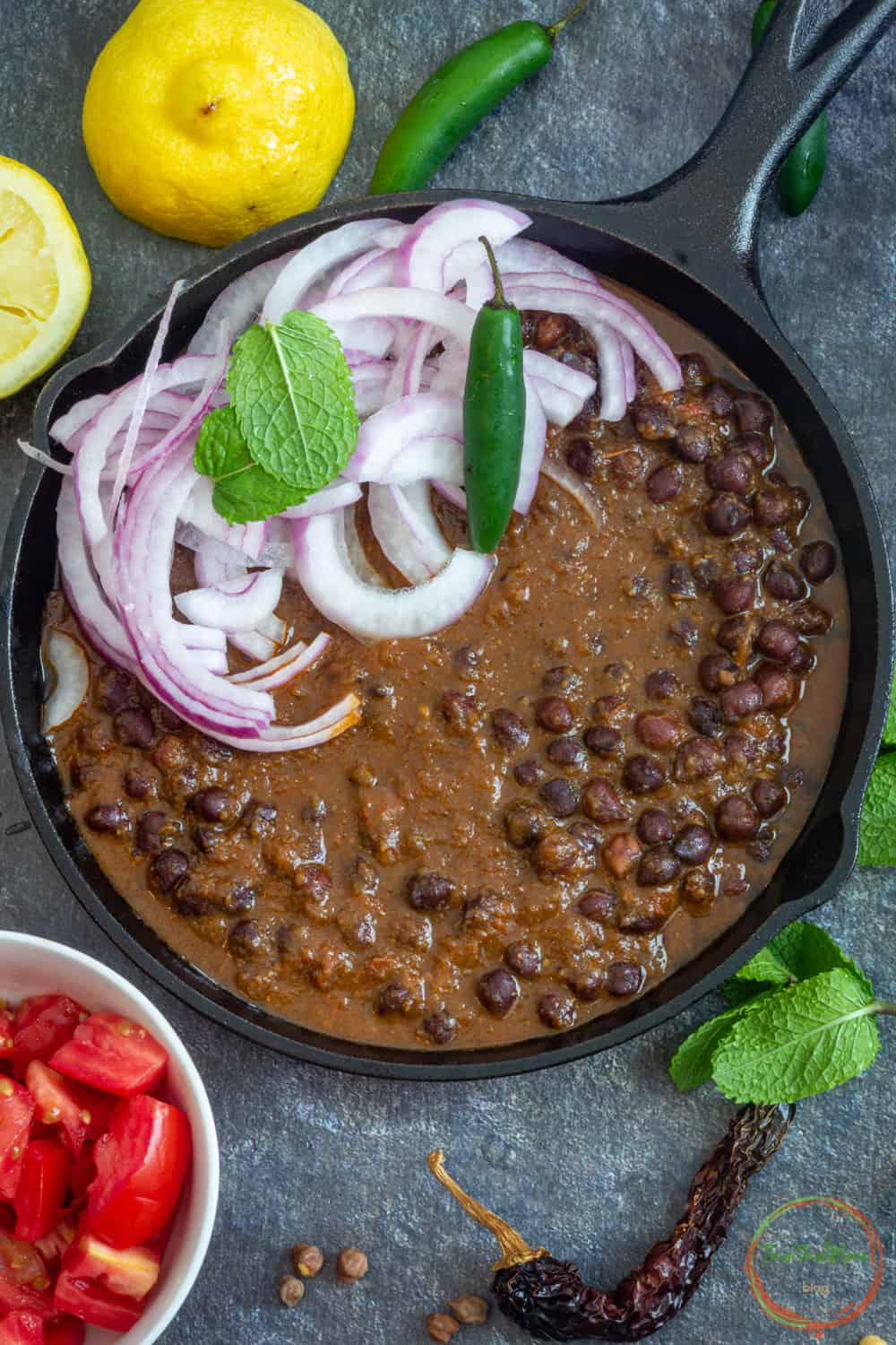 Black Chickpeas Curry garnished with sliced onions and green chili.