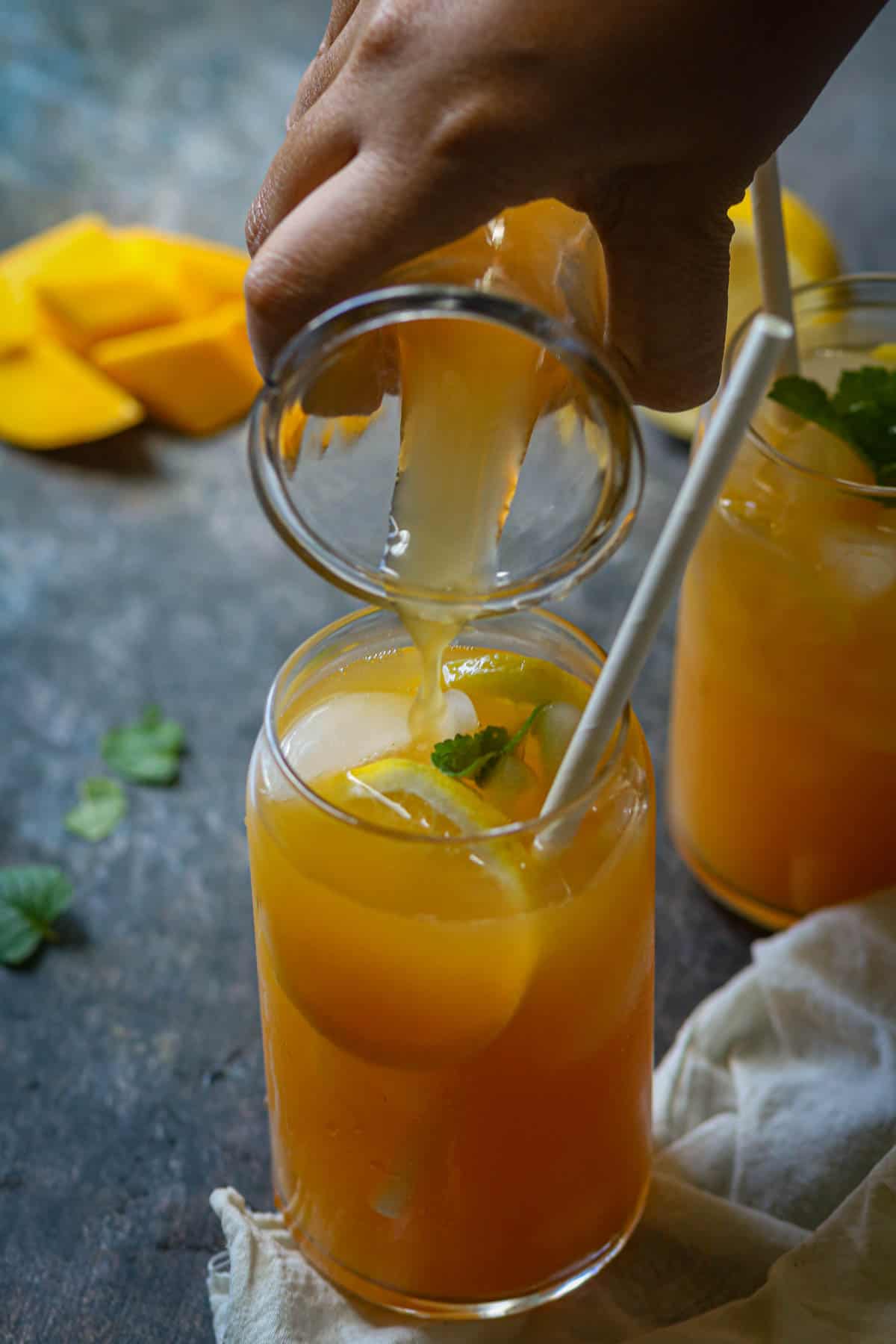 Pouring peach mango tea in glasses.