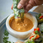 Dipping Vgean SImmer Rolls in Spicy Peanut Sauce.