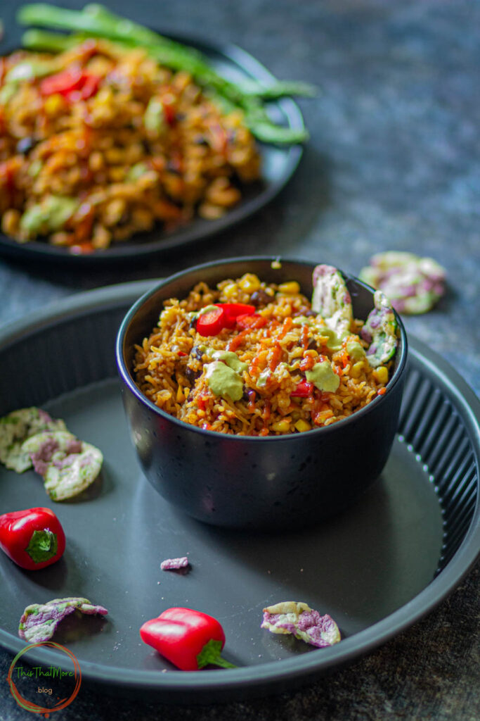 Enchilada rice in a black bowl garnished with some sauce and it can be served with some chips