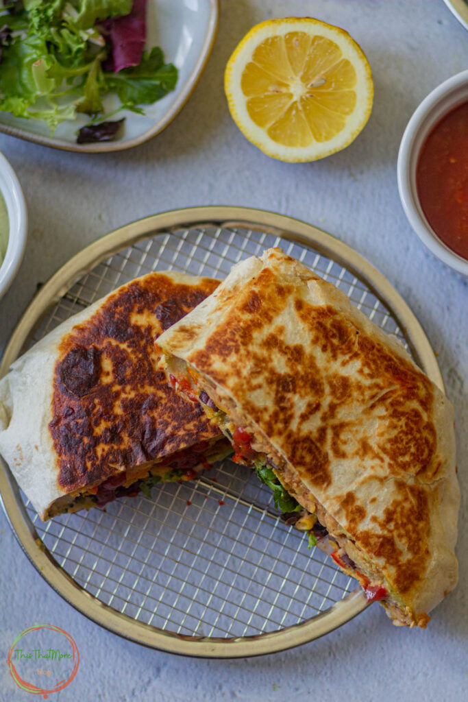 crunchwrap supreme in a plate along with salsa and lemon on the side