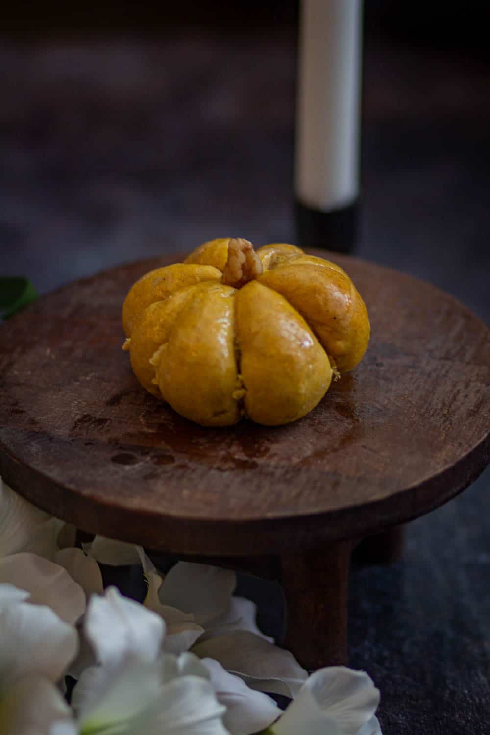 Pumpkin dinner roll on a cake stand with candle on the back