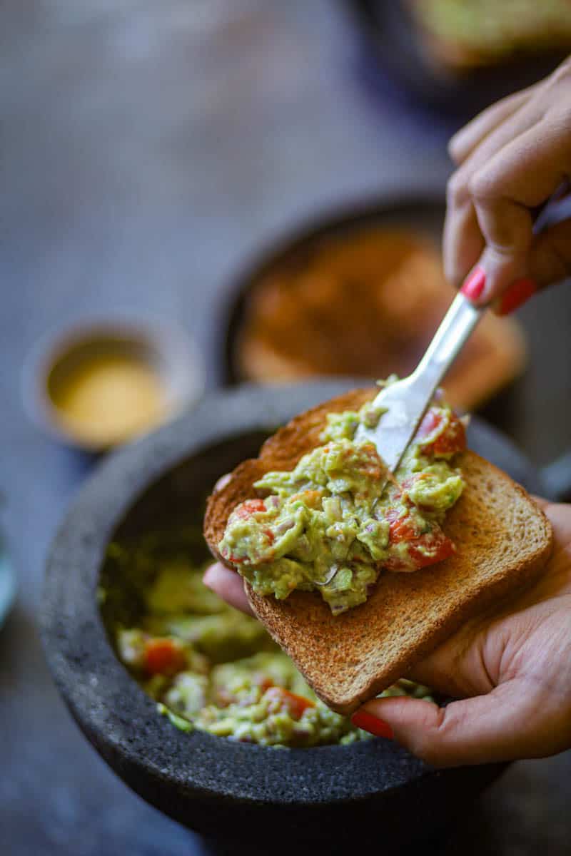 Spreading jalapeno guacamole over the toasted bread.