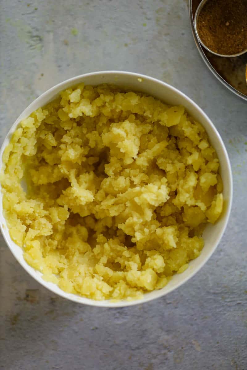 Mash the boiled potatoes in a bowl.