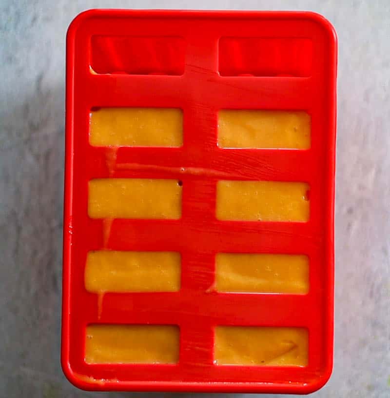 Pour mango pulp in popsicle molds.