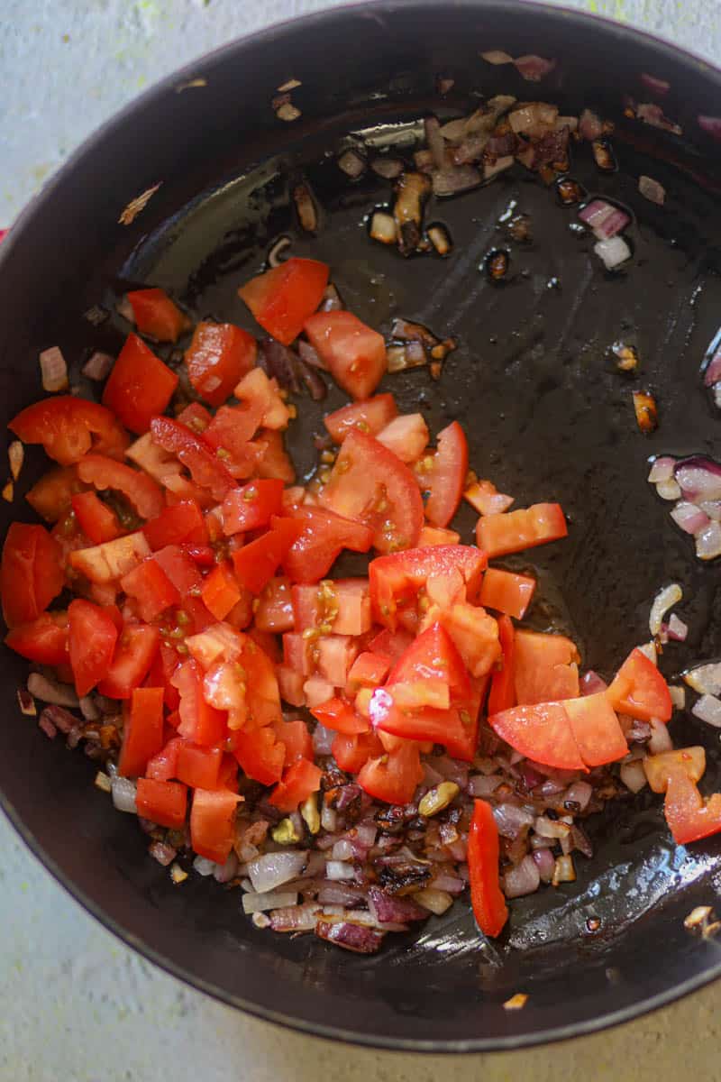 Once onions start to change color, add tomatoes.