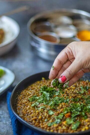 A side shot of green moong dal garnished with cilantro.