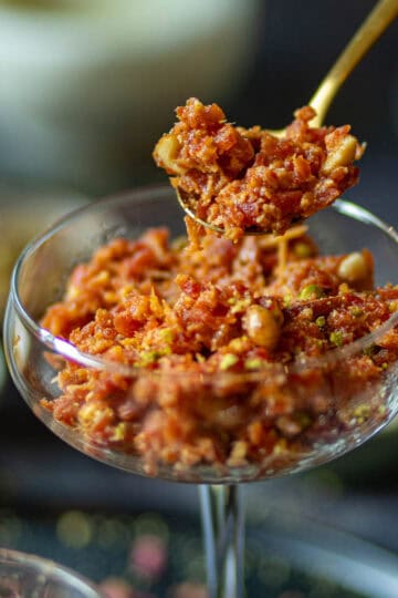 A close up shot of carrot halwa with khoya in a spoon.